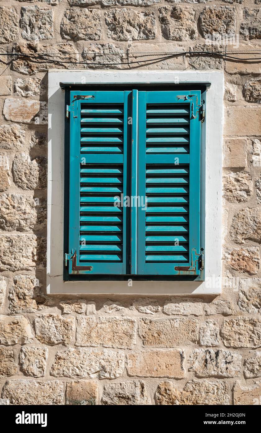 Altes Fenster mit geschlossenen Fensterläden an der Außenwand. Stockfoto