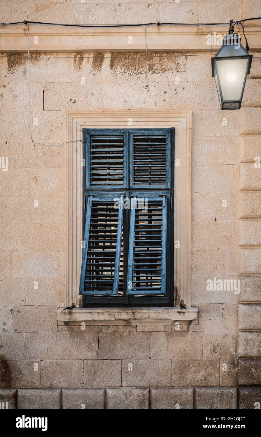 Altes Fenster mit blau gestrichenen Fensterläden. Stockfoto