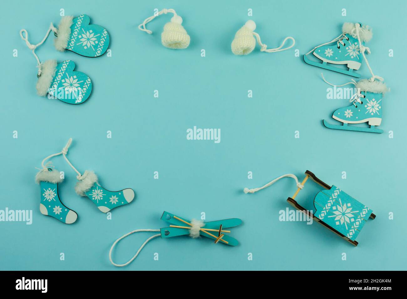 Blauer weihnachtlicher Hintergrund mit dekorativem Holzspielzeug - Skier, Schlitten, Schlittschuhe, Fäustlinge, Hut. Draufsicht. Eine Kopie des Raumes Stockfoto