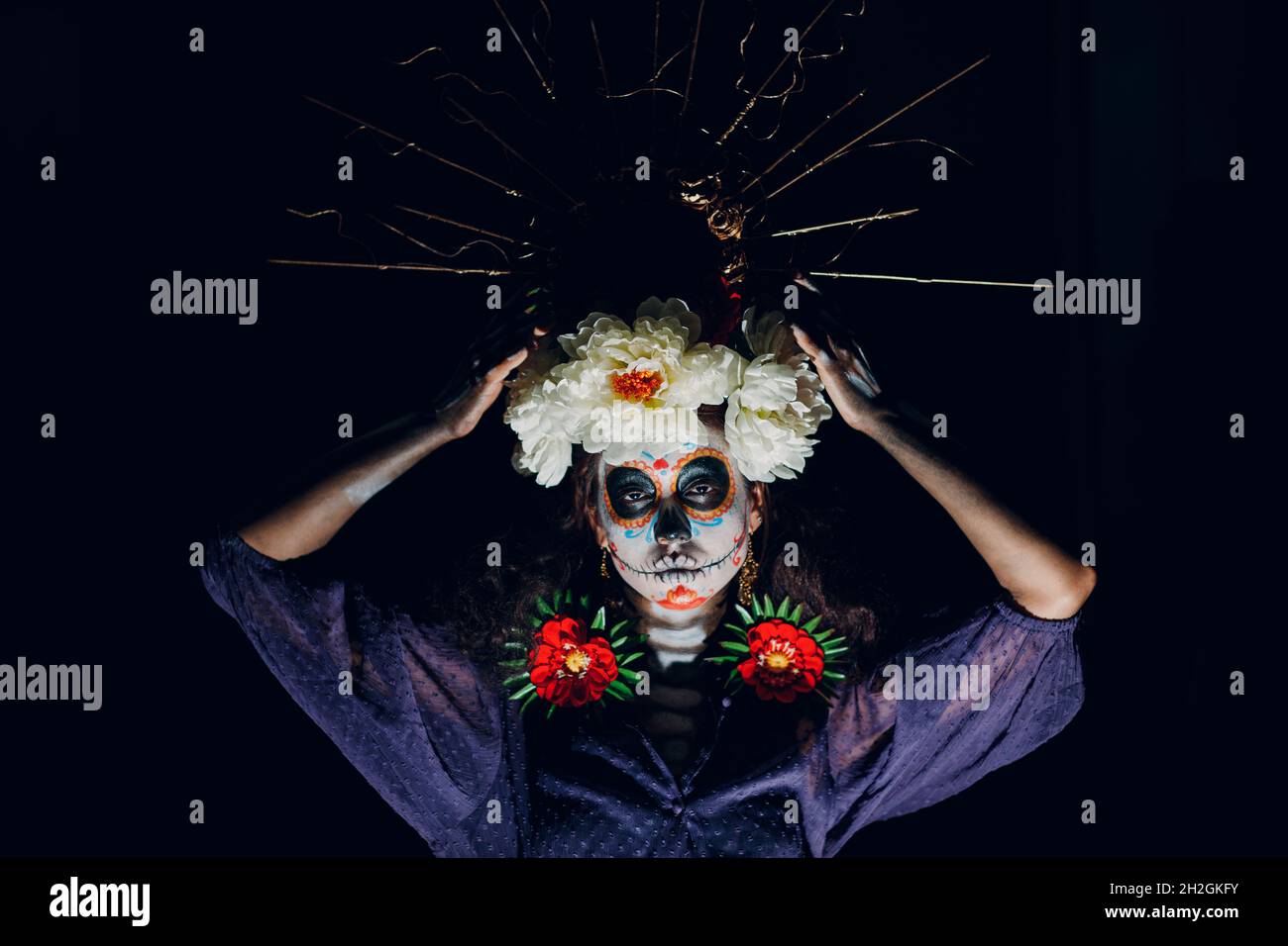 Frau mit mexikanischem Totenkopf halloween Make-up auf dunklem Hintergrund. Tag der Toten alias Dia de Muertos und traditionelle Halloween-Feier Stockfoto