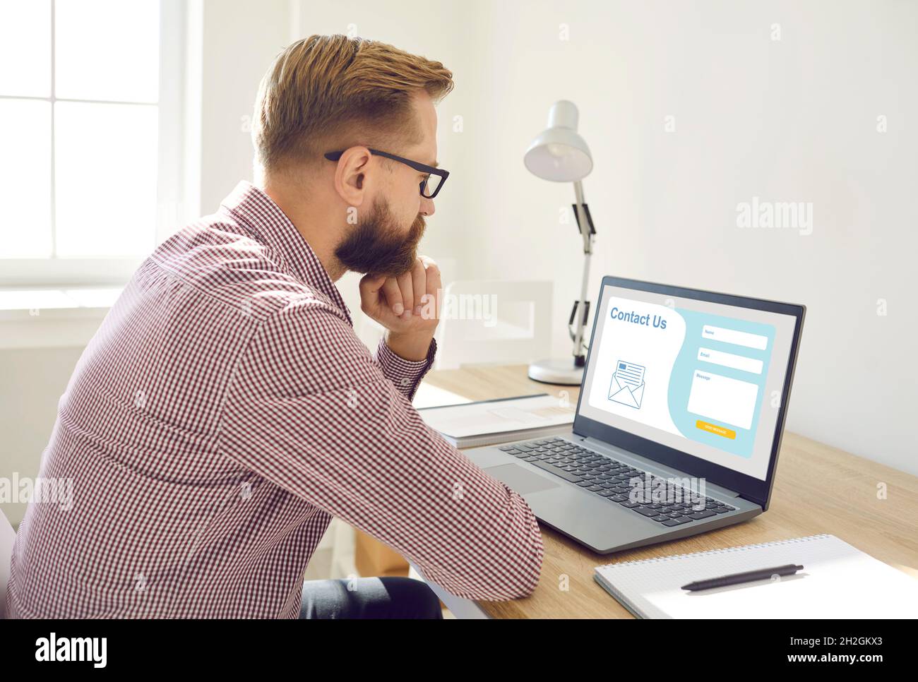 Mann sitzt und denken, was in Kontakt mit uns Formular auf Landing-Page-Website zu schreiben Stockfoto