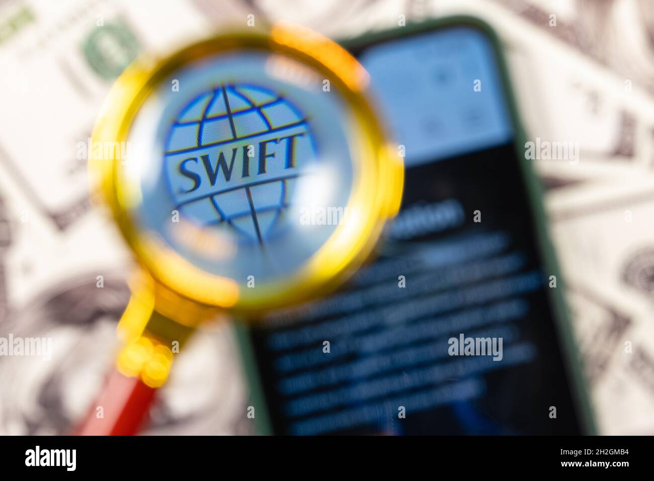 SWIFT ist das Netzwerk der Gesellschaft für weltweite Interbank Financial Telecommunication. SWIFT-Logo auf dem Smartphone-Bildschirm unter der Lupe. Stockfoto