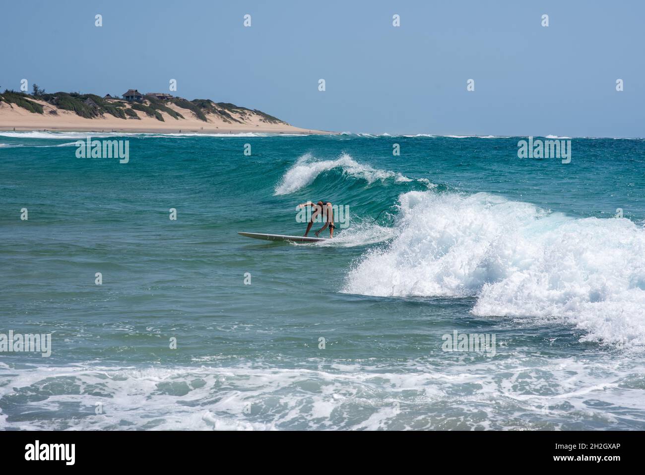 Weibliche Surferin, die Wellen entlang der Küste reitet Stockfoto