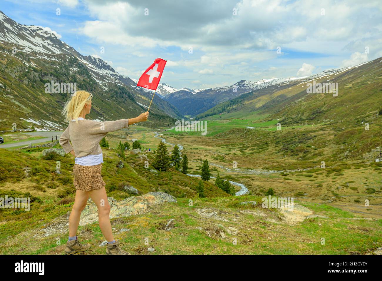 Frau mit schweizer Flagge auf der Panoramastraße des Fluela-Passes. Hochgebirgspass der Schweizer Alpen. Kanton Graubünden in der Schweiz. Stockfoto