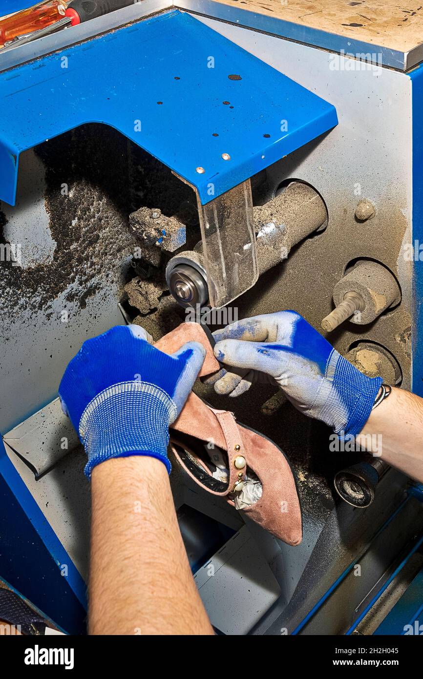 Junger Schuhmacher, der Schuhe in der Werkstatt flicken kann. Stockfoto