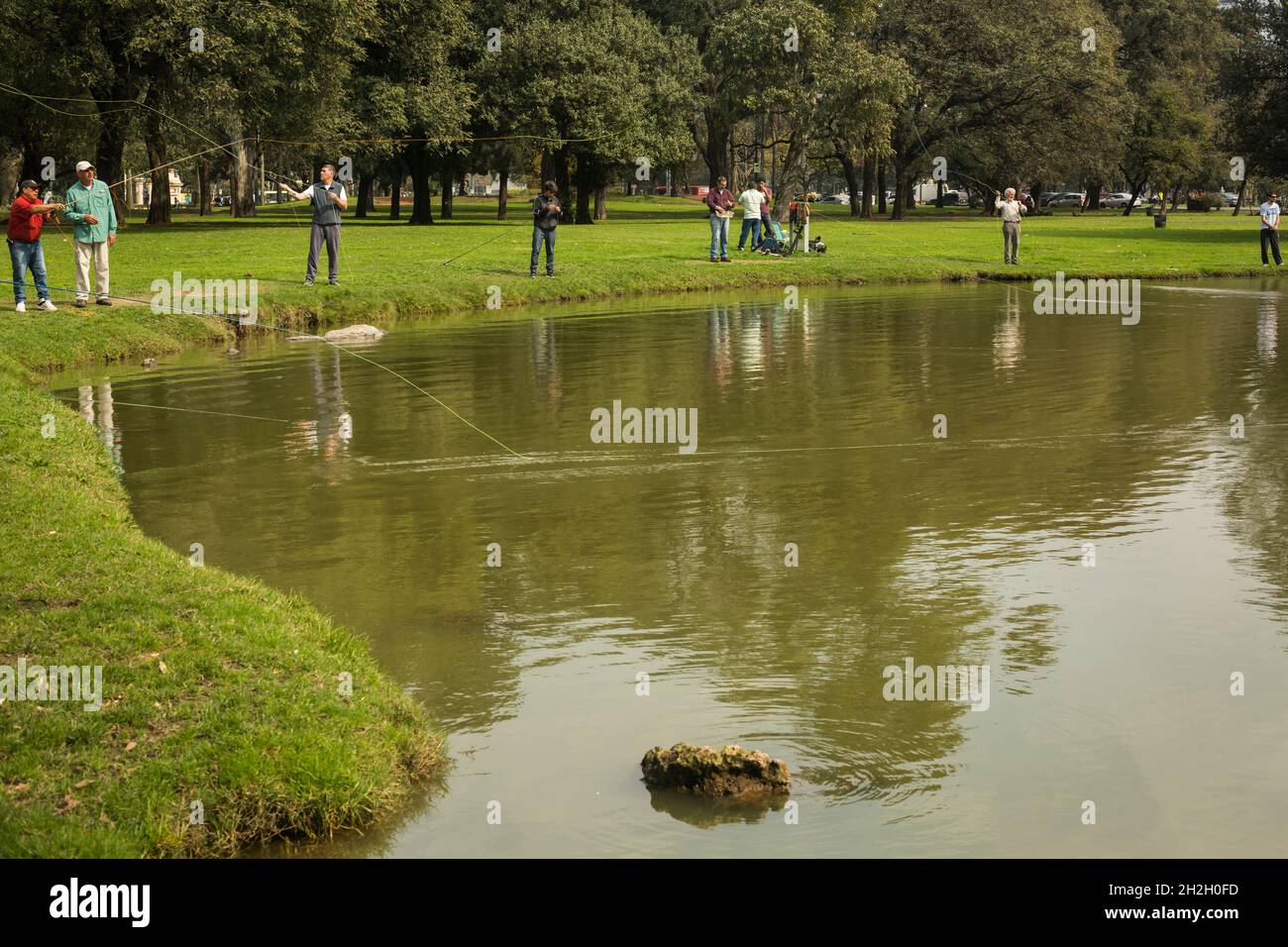 Horizontale Ansicht einer Gruppe von Männern, die in einem See in einem Palermo-Park, Buenos Aires, Argentinien, fischen Stockfoto