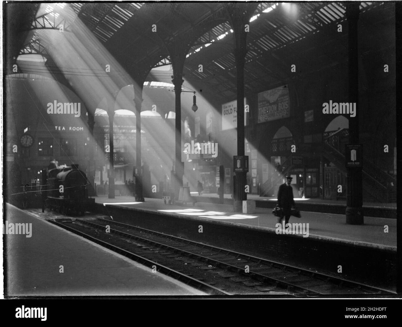 Liverpool Street Station, Liverpool Street, City of London, Greater London Authority, c1932. Ein Blick über das Bahnhofsgebäude an der Liverpool Street Station, der eine Dampfmaschine im Bahnhof zeigt, einen Gepäckträger, der auf einer Plattform Gepäck trägt, und Sonnenstrahlen, die durch das Dach scheinen. Stockfoto