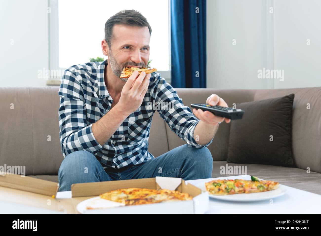 Mann, der beim Pizza-Essen Fernsehen schaute. Freizeit zu Hause verbringen Stockfoto