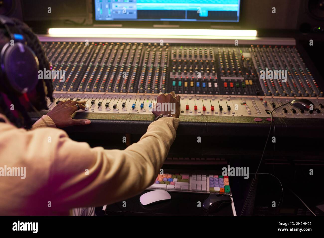 Rückansicht eines jungen Mannes, der im Aufnahmestudio Musik auf Audiogeräten kreide Stockfoto