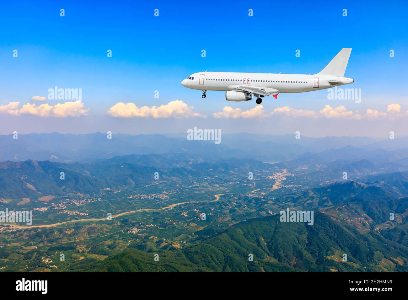Verkehrsflugzeug, das über blauem Himmel und weißen Wolken fliegt. Stockfoto