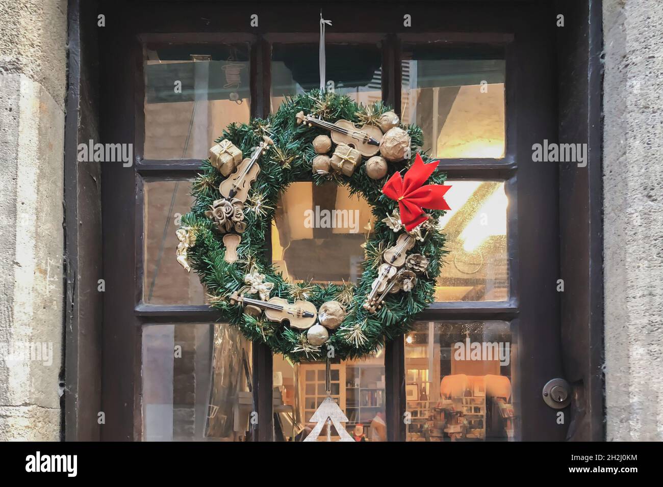 Weihnachtskranz mit kleinen Miniaturen an einer Glastür Stockfoto