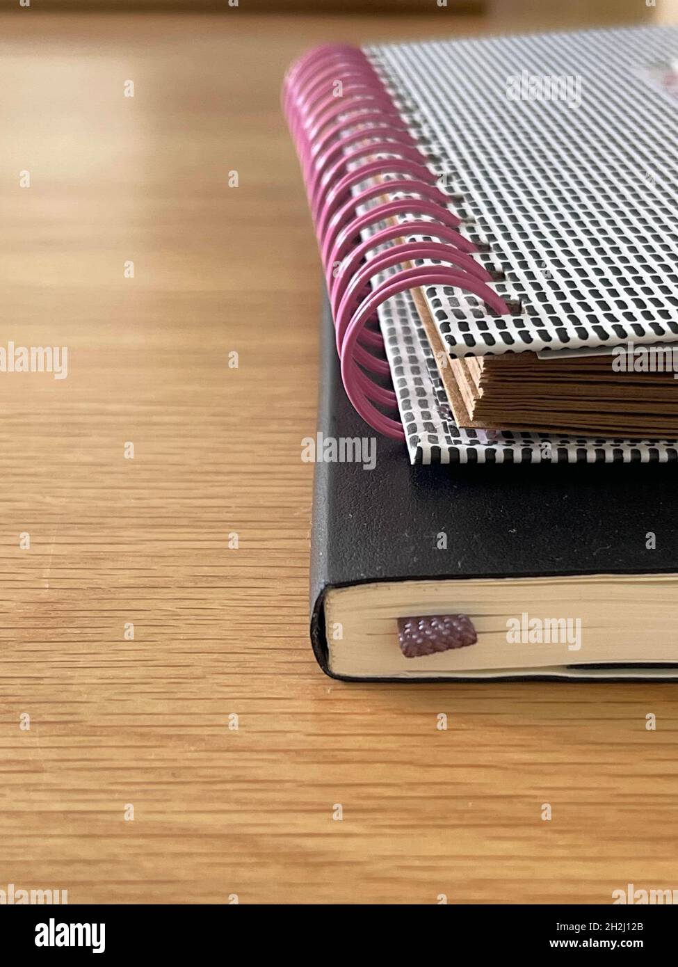 Vertikal beschnittene Nahaufnahme von gestapelten Notizbüchern auf dem Schreibtisch Stockfoto