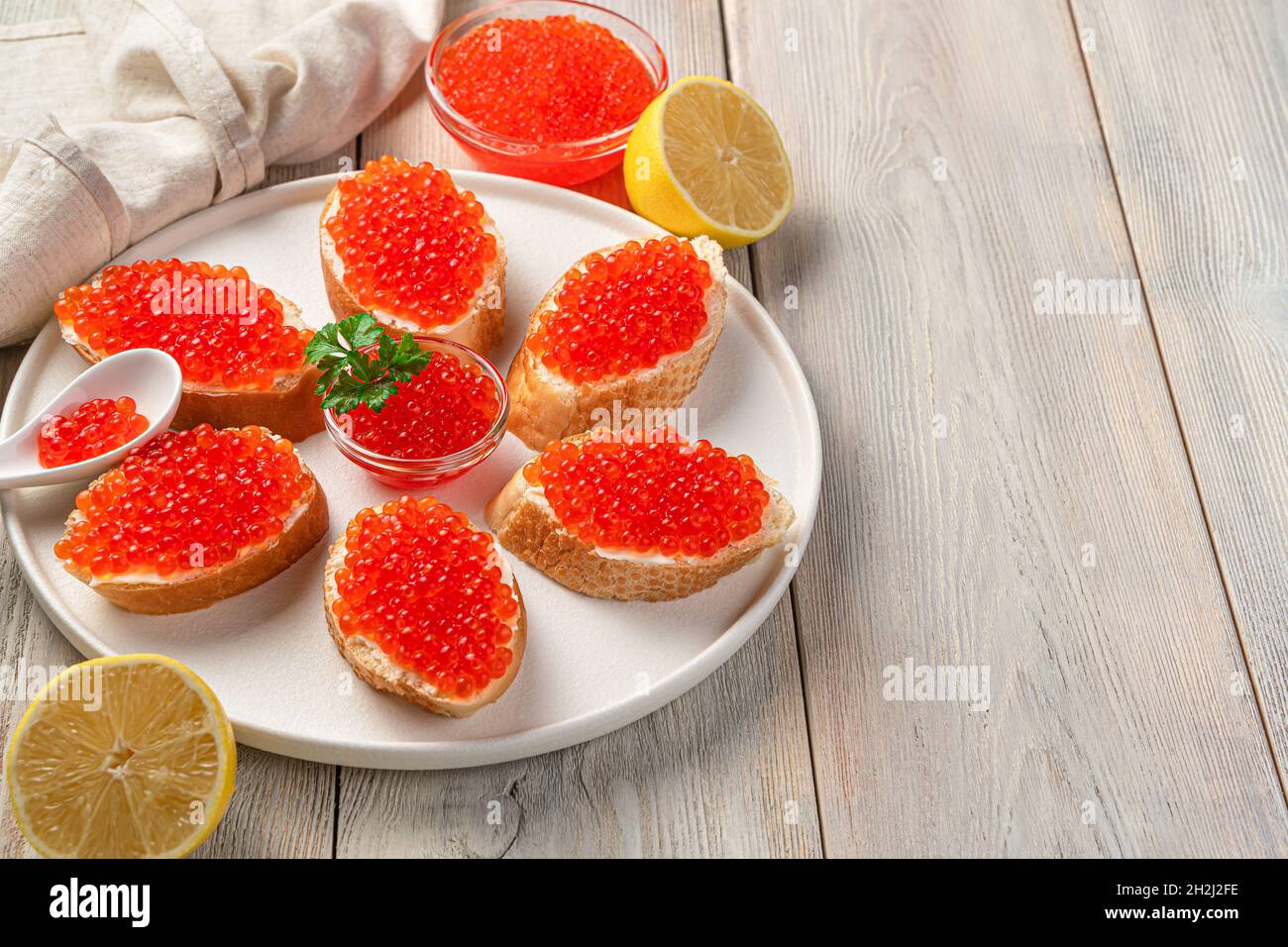 Sandwiches mit rotem Kaviar und Zitrone auf beigefarbenem Hintergrund. Seitenansicht, Kopierbereich. Stockfoto