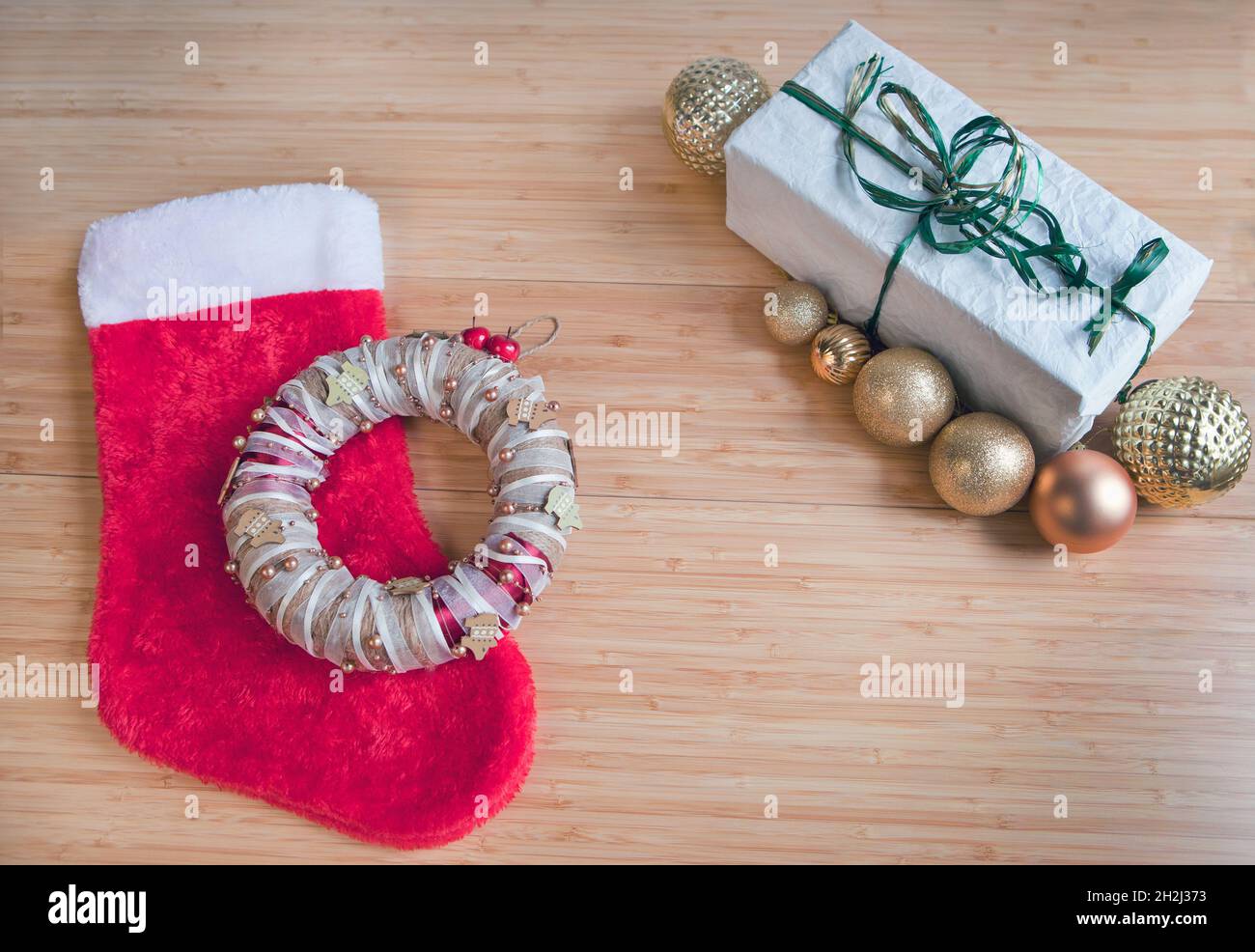 Rote Socke für Weihnachtsgeschenke, Geschenk auf recyceltem Papier verpackt, goldene Kugeln Dekorationen auf dem Tisch. Stockfoto