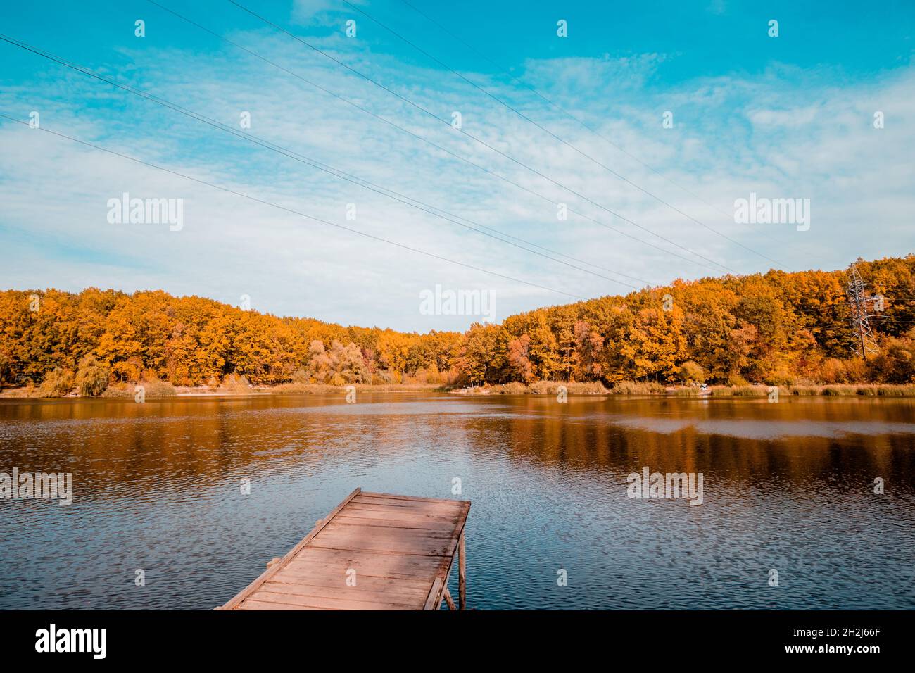Transparenter, klarer See mit Holzsteg im Herbst. Herbstlandschaft. Stockfoto