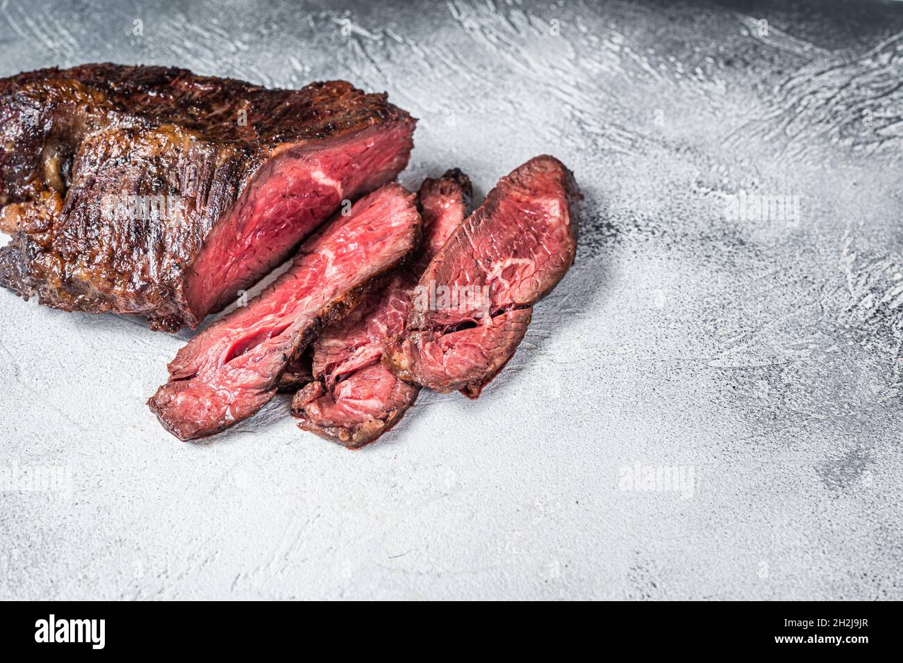Gebratener Aufhänger oder Onglet-Rindersteak in Scheiben auf einem Tisch. Weißer Hintergrund. Draufsicht. Speicherplatz kopieren Stockfoto