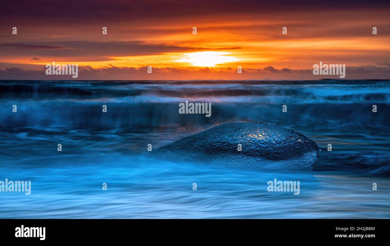 Eisbrocken auf dem schwarzen Sand von Diamond Beach. Eis wird am Strand von der nahe gelegenen Jokulsarlon Gletscherlagune abgelagert. Sonnenaufgang in Island. Stockfoto