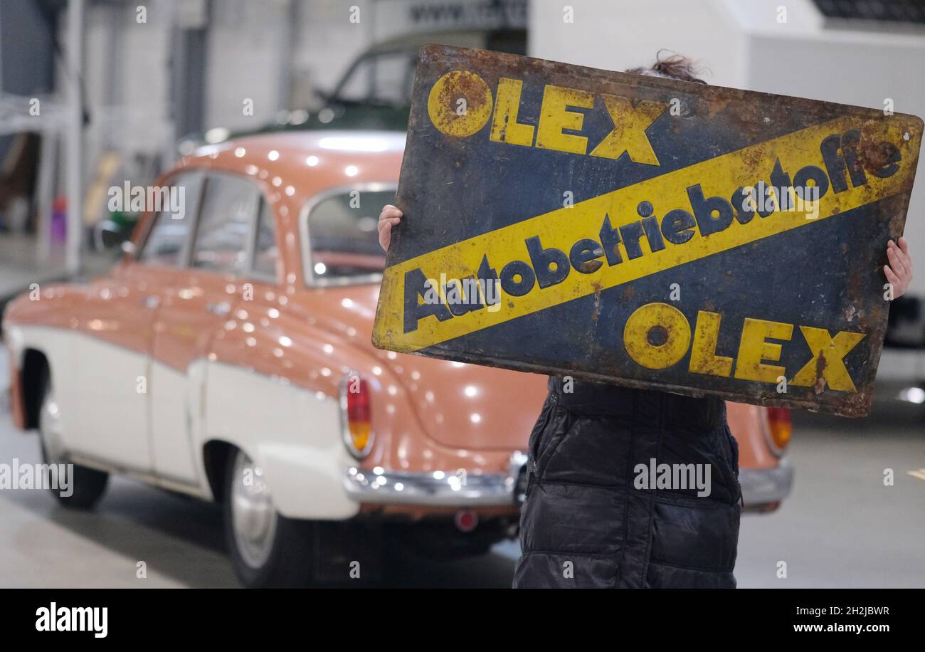 Halle, Deutschland. Oktober 2021. Ein Händler für alte Automobilteile hält ein altes Werbeschild in den Händen. Das Stück wird am 23. Und 24. Oktober 2021 auf dem Messegelände in Halle auf der Oldtema, dem Oldtimer- und Teilemarkt, angeboten. Mehr als 150 Händler aus Deutschland und den Nachbarländern werden anwesend sein. Quelle: Sebastian Willnow/dpa-Zentralbild/ZB/dpa/Alamy Live News Stockfoto