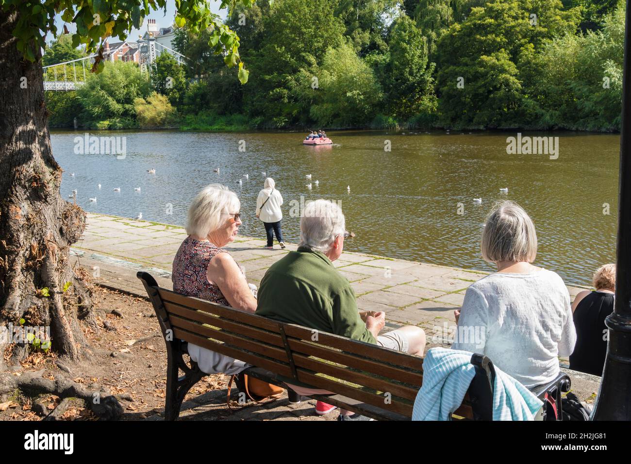 Drei Personen sitzen und beobachten die Aktivität des Flusses auf dem Fluss Dee Chester 2021 Stockfoto