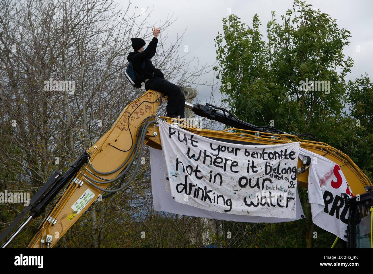 Chalfont St Peter, Großbritannien. Oktober 2021. Stopp HS2-Demonstranten aus dem Kriegslager Wendover aktiver Widerstand besetzten einen Bagger, der heute vor dem Gelände des HS2 Chalfont St Peter Hochwasserschutzarbeiten durchführte, wo die Überschwemmungen auf der Straße angeblich viel schlimmer wurden, seitdem HS2 vor Ort Bäume und Felder geräumt hat. Es wurde berichtet, dass HS2 1,600 Kubikmeter potenziell stark verschmutzenden Bentonits in den Kalkaquifer am Standort verloren hat. Quelle: Maureen McLean/Alamy Live News Stockfoto