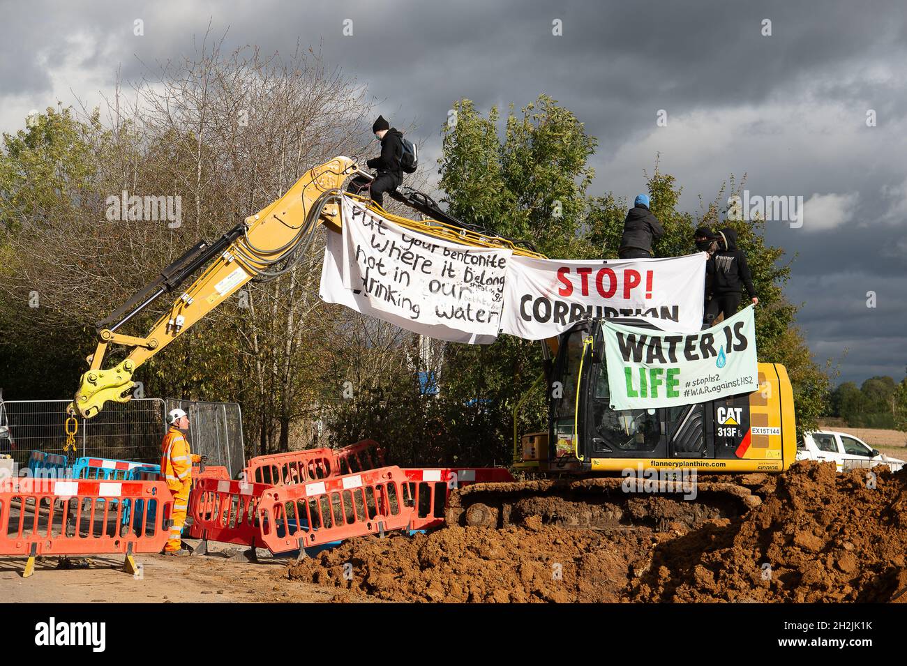 Chalfont St Peter, Großbritannien. Oktober 2021. Stopp HS2-Demonstranten aus dem Kriegslager Wendover aktiver Widerstand besetzten einen Bagger, der heute vor dem Gelände des HS2 Chalfont St Peter Hochwasserschutzarbeiten durchführte, wo die Überschwemmungen auf der Straße angeblich viel schlimmer wurden, seitdem HS2 vor Ort Bäume und Felder geräumt hat. Es wurde berichtet, dass HS2 1,600 Kubikmeter potenziell stark verschmutzenden Bentonits in den Kalkaquifer am Standort verloren hat. Quelle: Maureen McLean/Alamy Live News Stockfoto