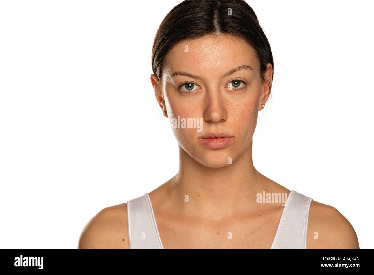 Schöne junge ernsthafte Frau ohne Make-up auf weißem Hintergrund Stockfoto