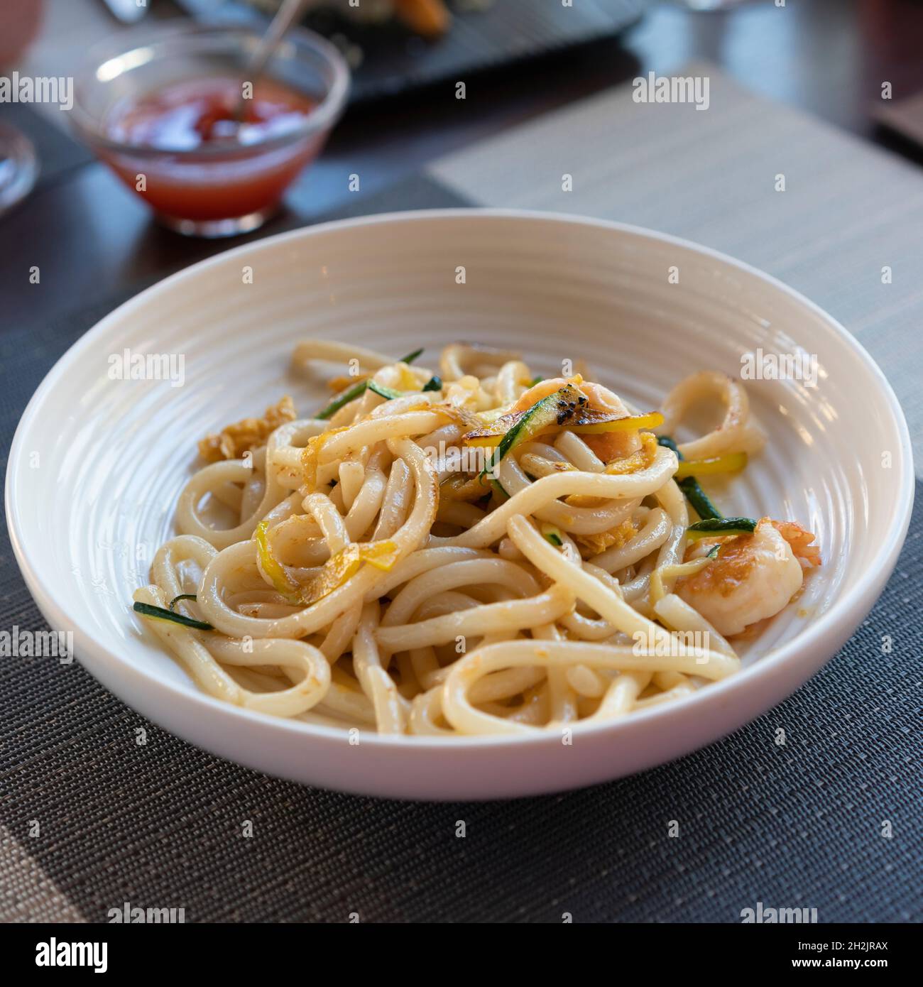 Vegetarisches Yaki Udon gesundes japanisches Gericht im Restaurant, Hintergrund Chilisauce. Stockfoto