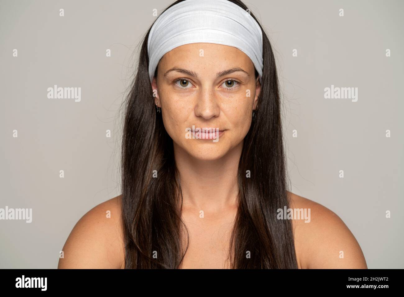 Porträt einer jungen Frau ohne Make-up und Stirnband auf grauem Hintergrund Stockfoto