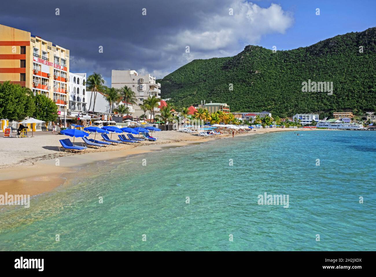 Touristen sonnen sich am Sandstrand mit Palmen an der Great Bay in der Hauptstadt Philipsburg des niederländischen Inselteils Sint Maarten in der Karibik Stockfoto