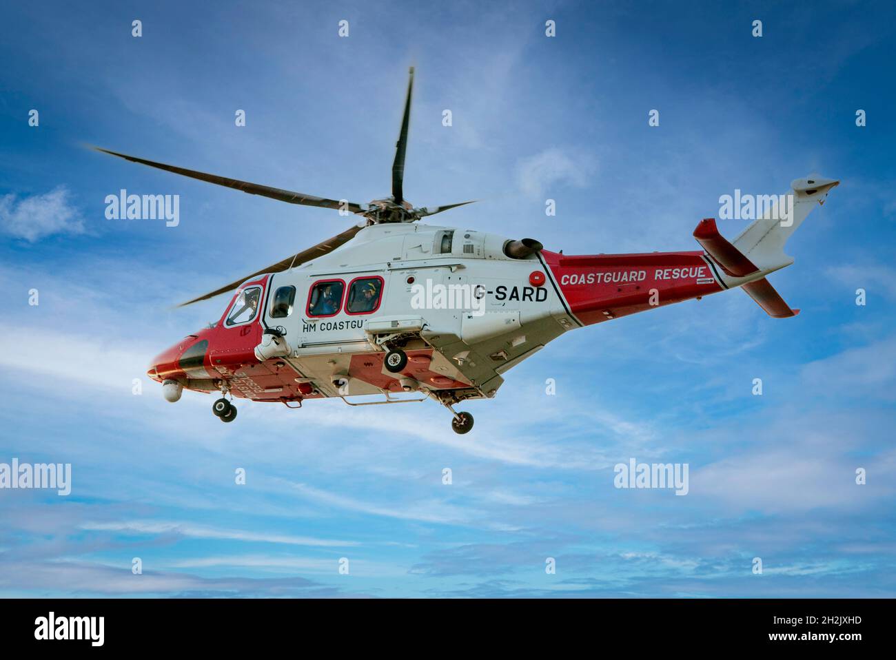 HM Küstenwache Rettungshubschrauber fliegt in einem blauen Himmel, aus nächster Nähe. Stockfoto