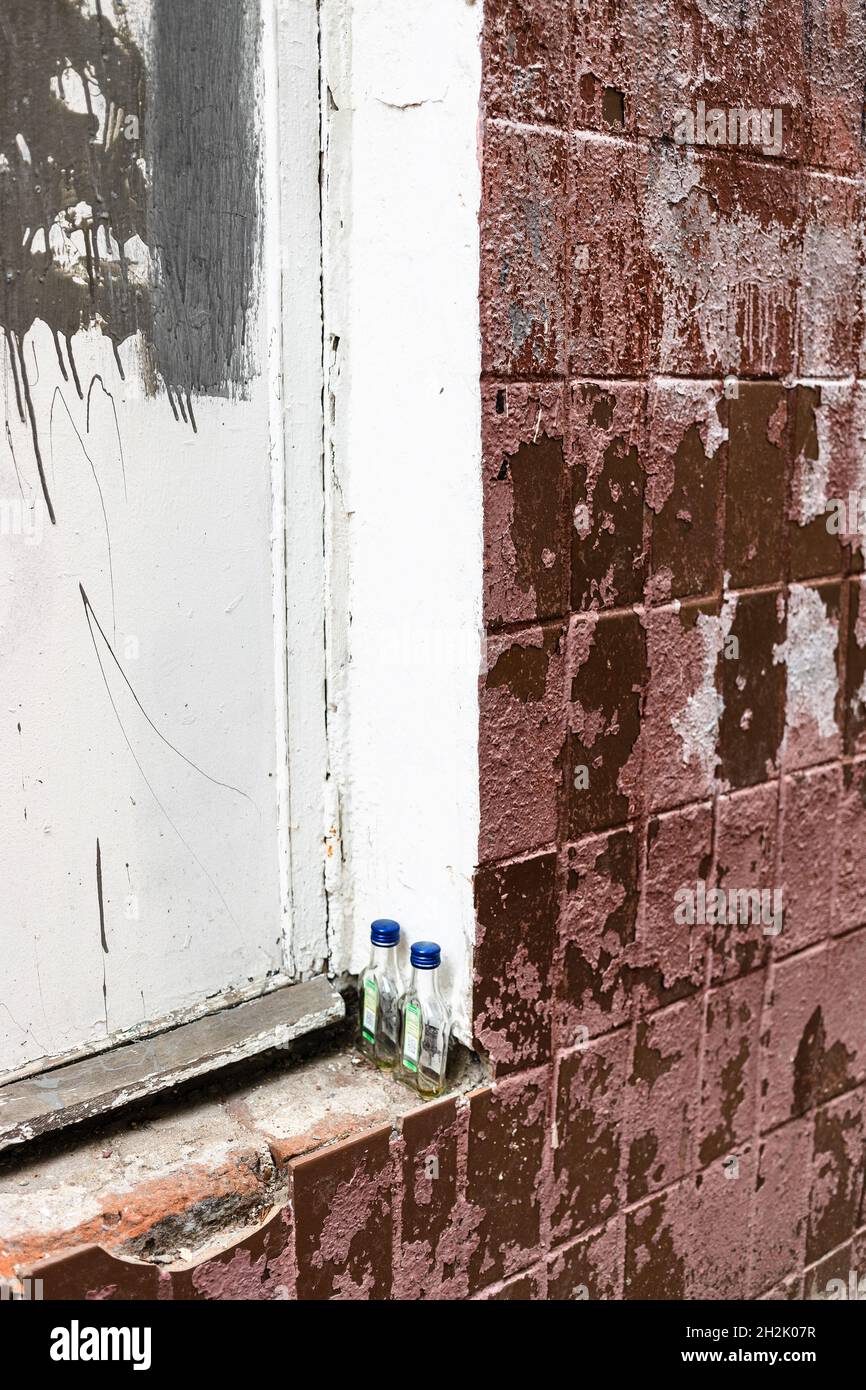 Ein Paar betrunkene Viertel-Liter-Flaschen auf dem äußeren Fensterbrett eines alten, bewirtschafteten, schäbigen Hauses Stockfoto