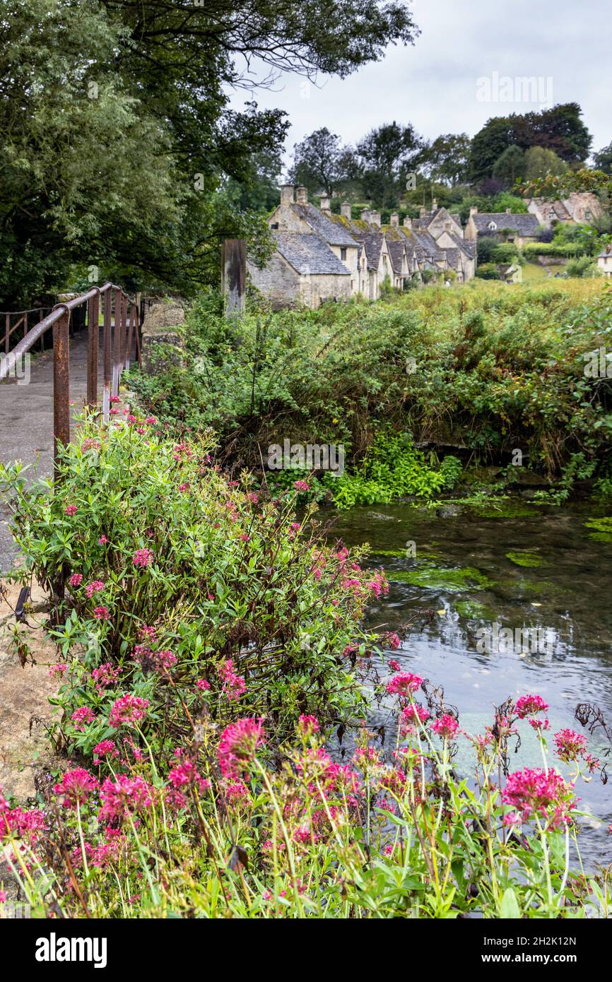 Eine kleine historische Steinbrücke über den Fluss Coln, die zur Arlington Row in Bibury Village in den Cotswolds, Gloucestershire, England führt. Stockfoto