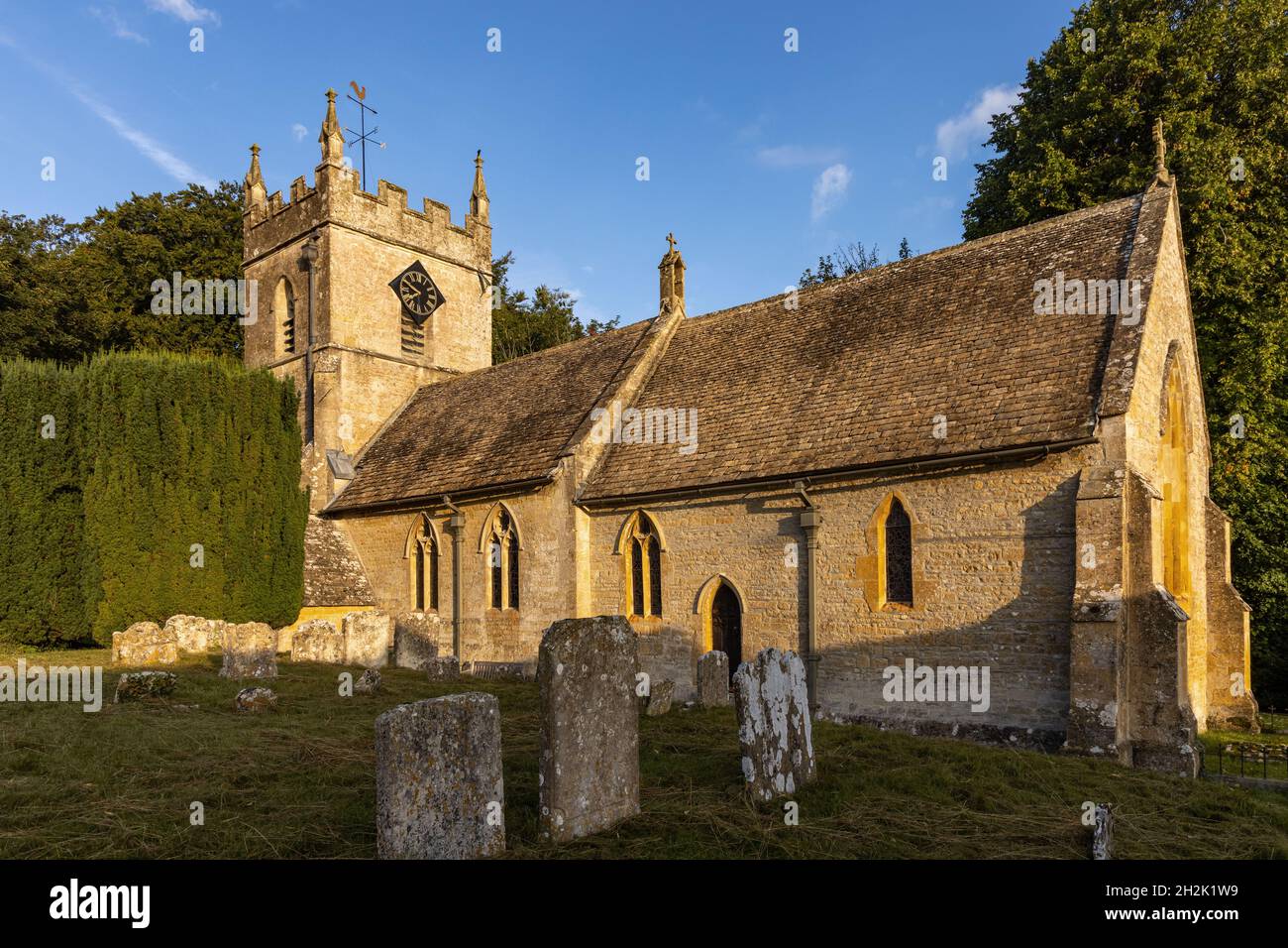 Die Morgensonne erleuchtet die wunderschöne St. Peter's Kirche im malerischen Cotswold Dorf Upper Slaughter in Gloucestershire, England. Stockfoto