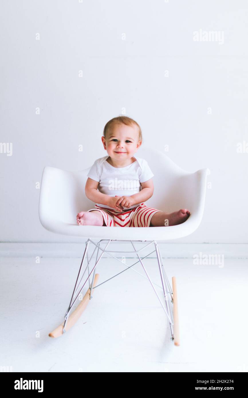 Ein kleiner Junge sitzt in einem modernen Muschelstuhl Stockfoto