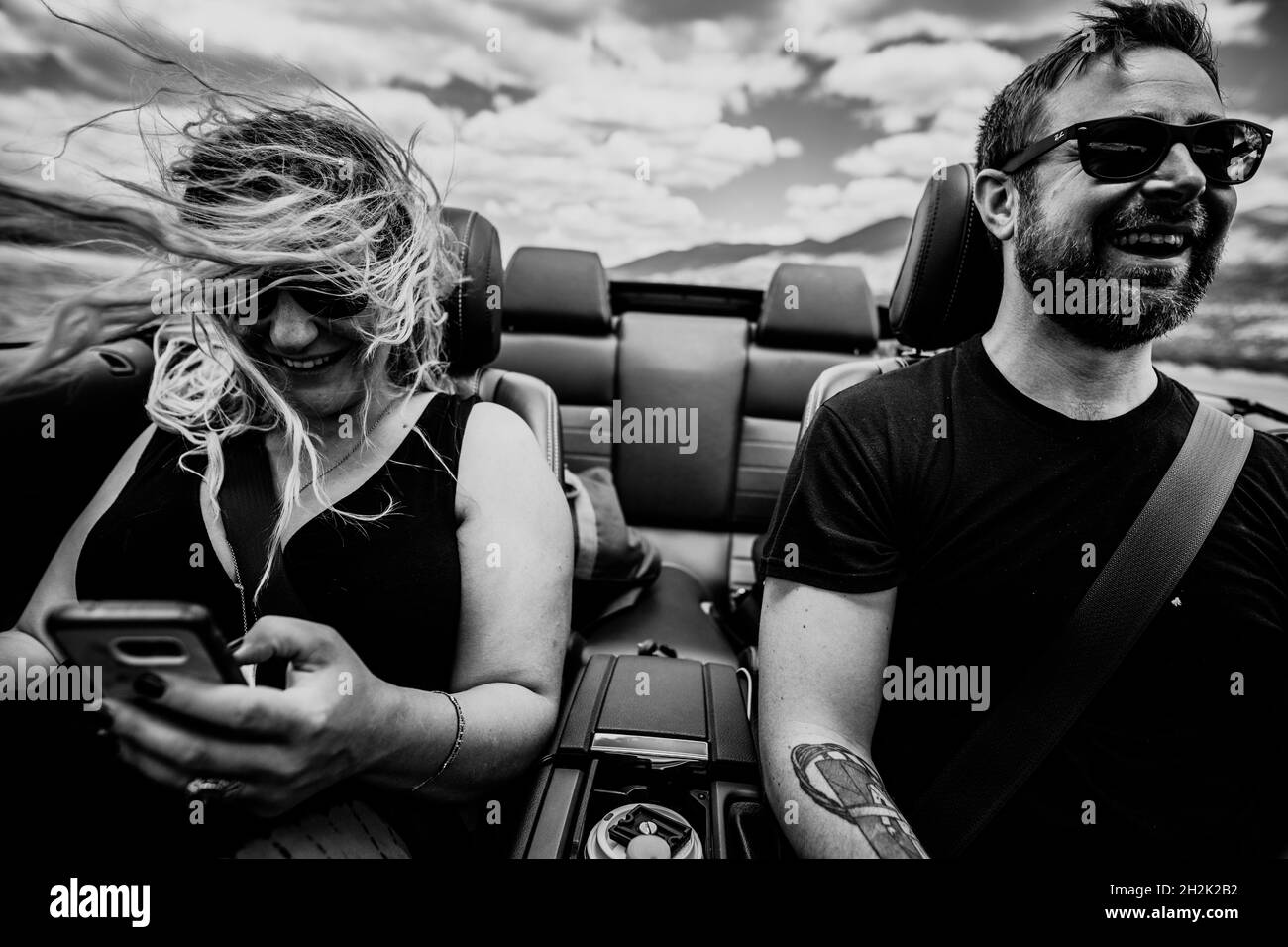 Glückliches Paar auf einem Roadtrip in einem Cabriolet, das in den Bergen unterwegs ist Stockfoto