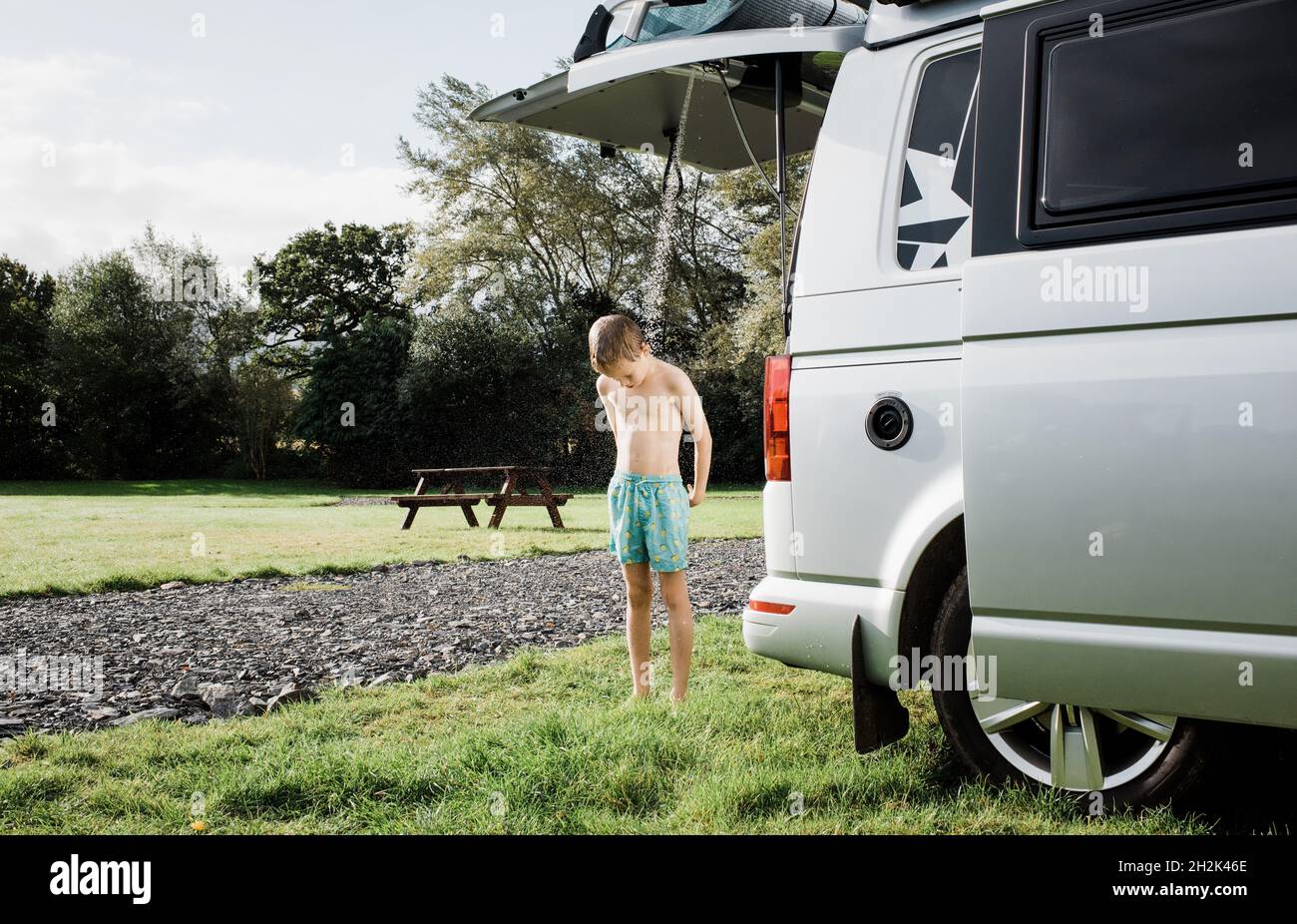Junge genießt Dusche im Freien, während Sie in einem Wohnmobil campen Stockfoto