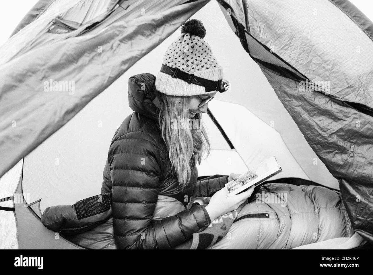 Frau saß in ihrem Zelt und las, während sie solo campte Stockfoto