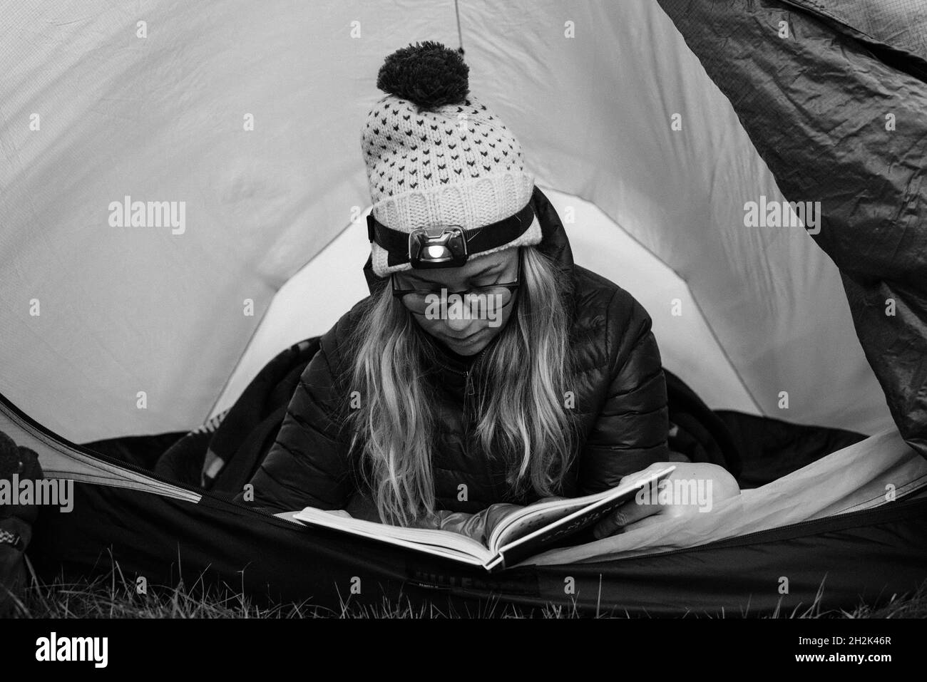 Frau lag in ihrem Zelt und las, während sie alleine campte Stockfoto