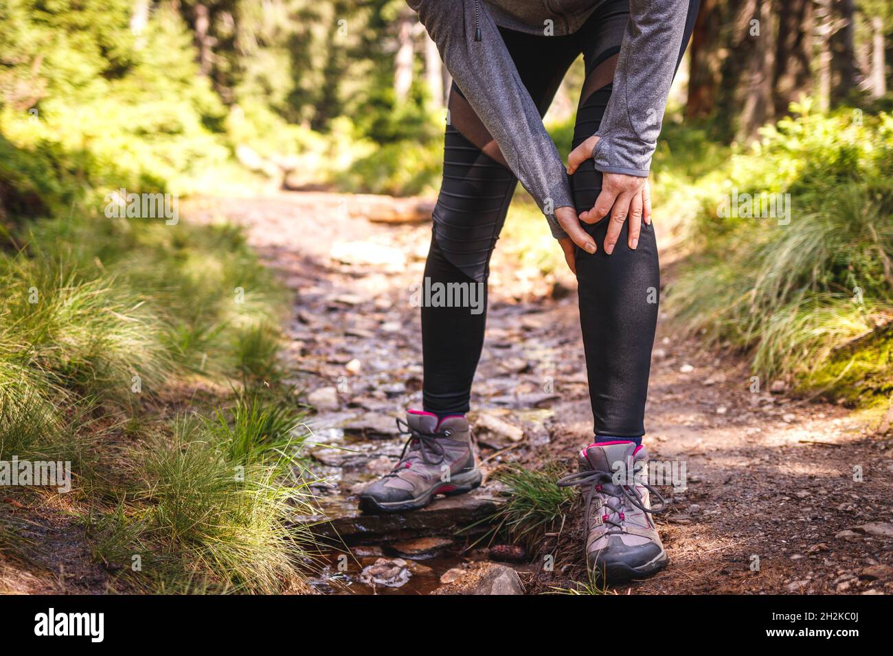 Frau mit Knieschmerzen. Tourist verletzt während der Wanderung. Weibliche Wandererin mit Gesundheitsproblem Stockfoto