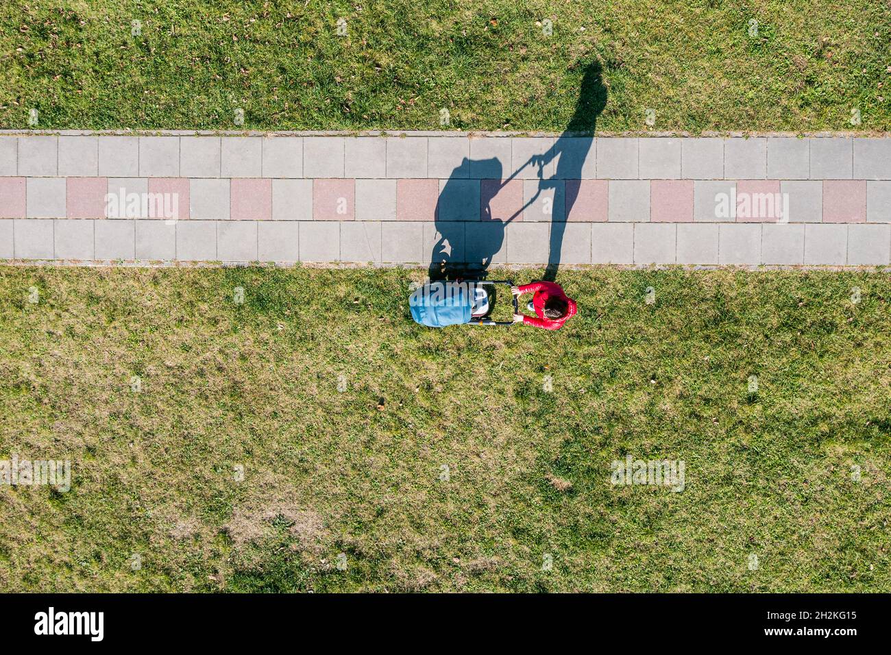 Luftaufnahme eines Elternteils mit einem Kinderwagen bei einem Spaziergang an sonnigen Tagen, Perspektive direkt darüber Stockfoto