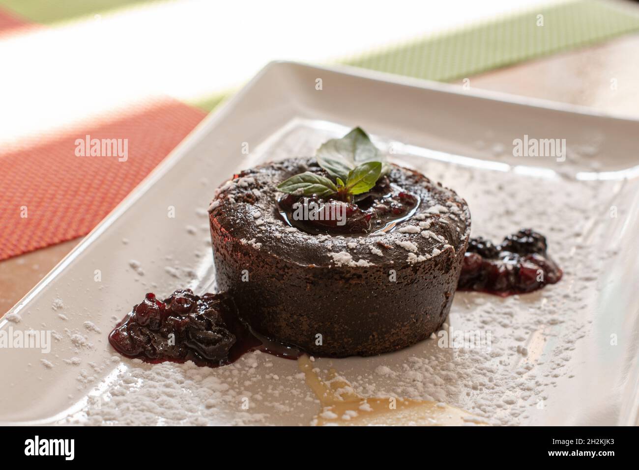 Köstliches Schokoladenkuchen-Dessert mit roter Beerenmarmelade und Puderzucker Stockfoto