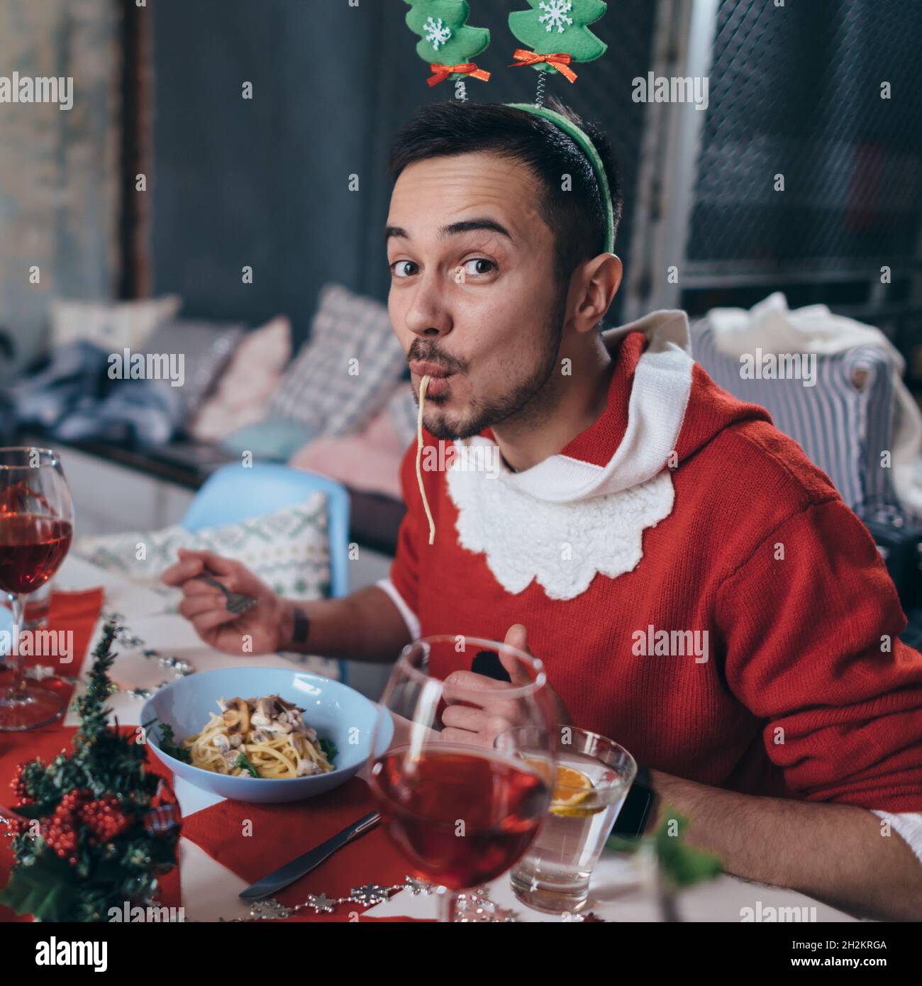 Mann im Weihnachtsmannkostüm, der Pasta, Spaghetti isst Stockfoto