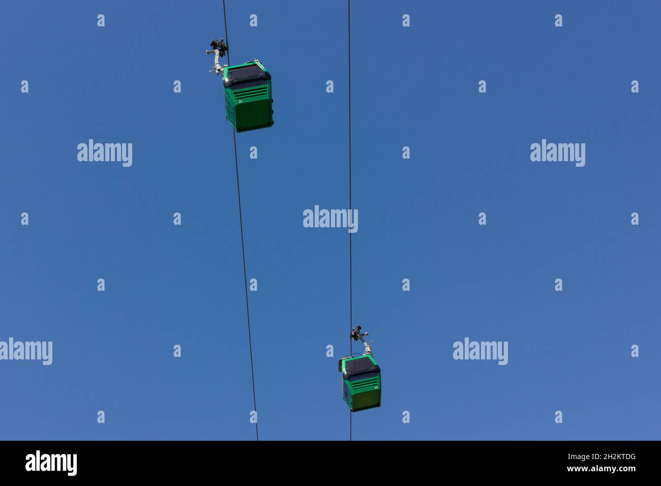 Grüne Seilbahnen über dem blauen Himmel von unten. Konzept für Touristenattraktionen Stockfoto