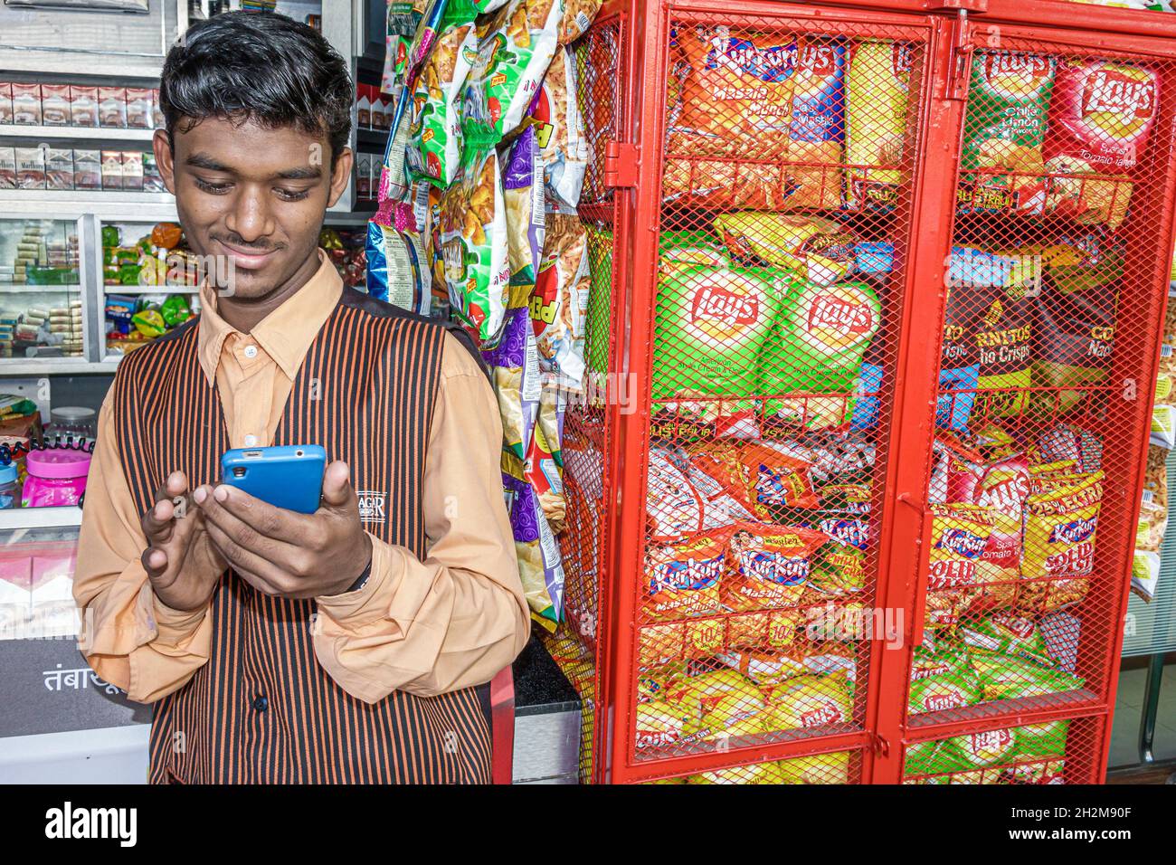 Mumbai Indien, Apollo Bandar Strand Road, Manager Convenience Store, Smartphone Handy SMS suchen Nachrichten, Junk-Food-Snack Lay's Kartoffelchips Stockfoto