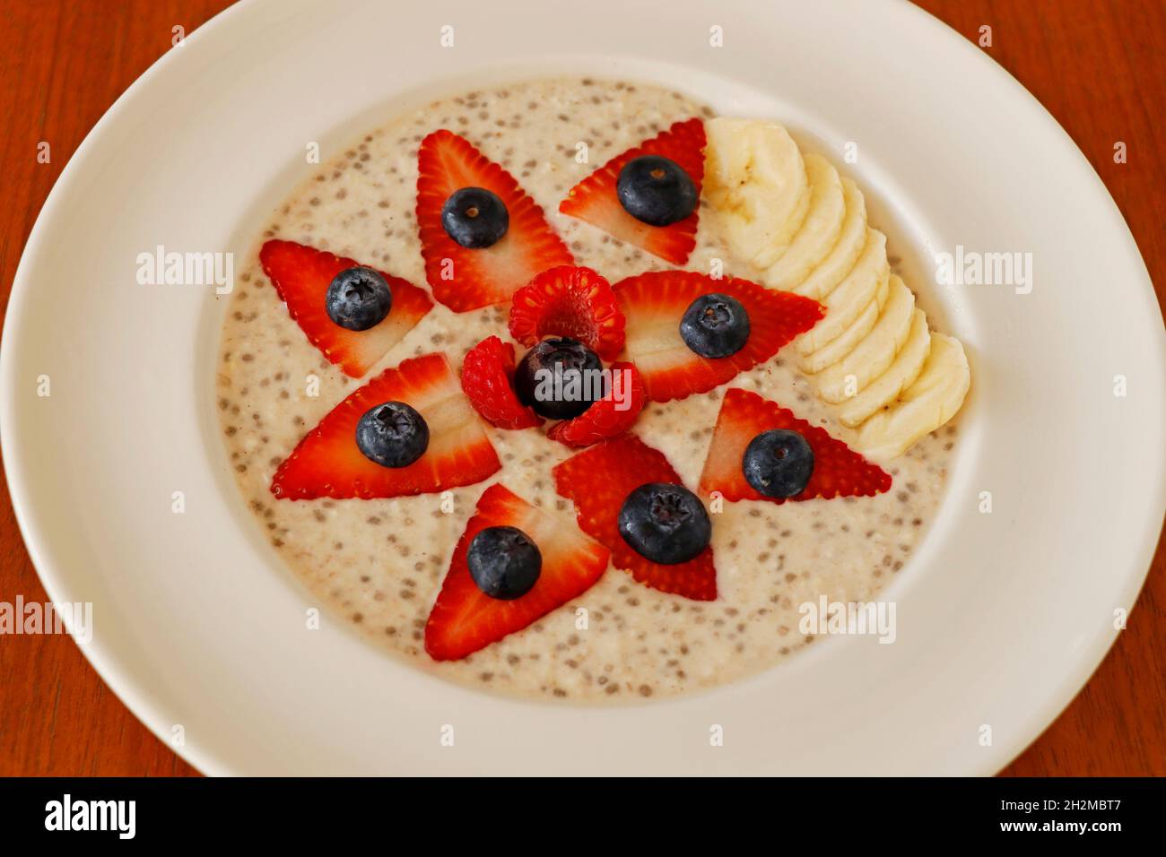 Hausgemachter Haferbrei, der in Mandelmilch mit Beeren und Banane gekocht wird Stockfoto