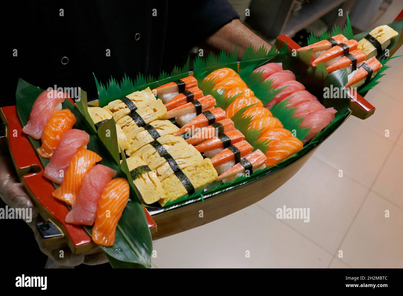 Eine große Auswahl an japanischen Sushi-Brötchen in einem Boot, inklusive Lachs, Thunfisch, Krabben, Garnelen usw. Stockfoto