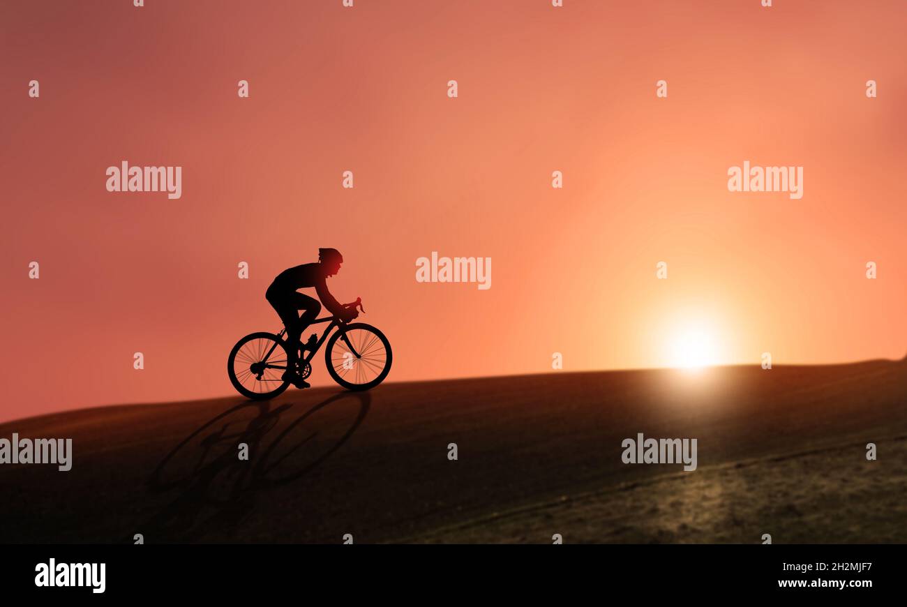 Radsportler Silhouette radelt bei Sonnenuntergang auf einem Berghang. Junger Mann radelt vor einem schönen orangefarbenen Himmel und glänzendem Sonnenlicht. Stockfoto