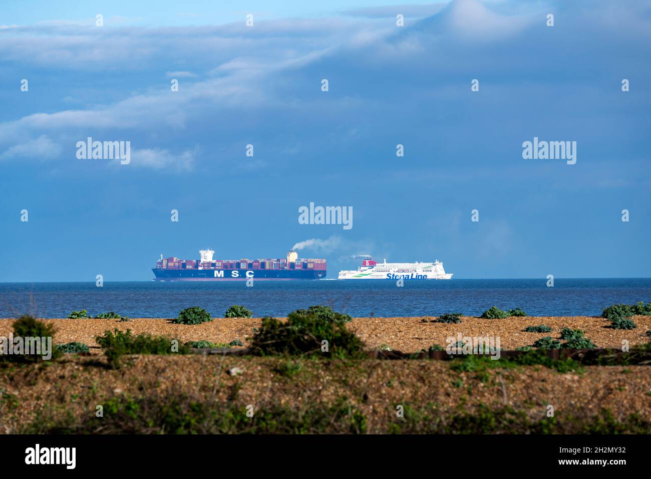 Containerschiff und Passagierfähre, die in der Nähe der Küste von Suffolk vorbeifahren Stockfoto