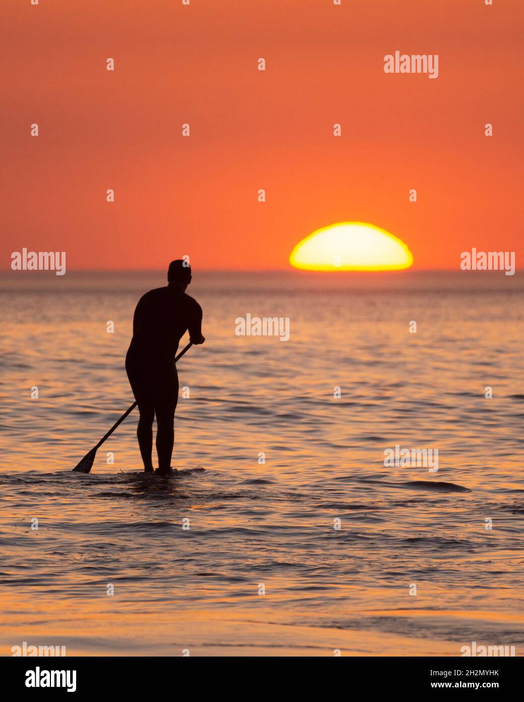 Stand Up Paddle Boarder bei Sonnenuntergang am Croyde Beach - Croyde, Devon, Großbritannien Stockfoto