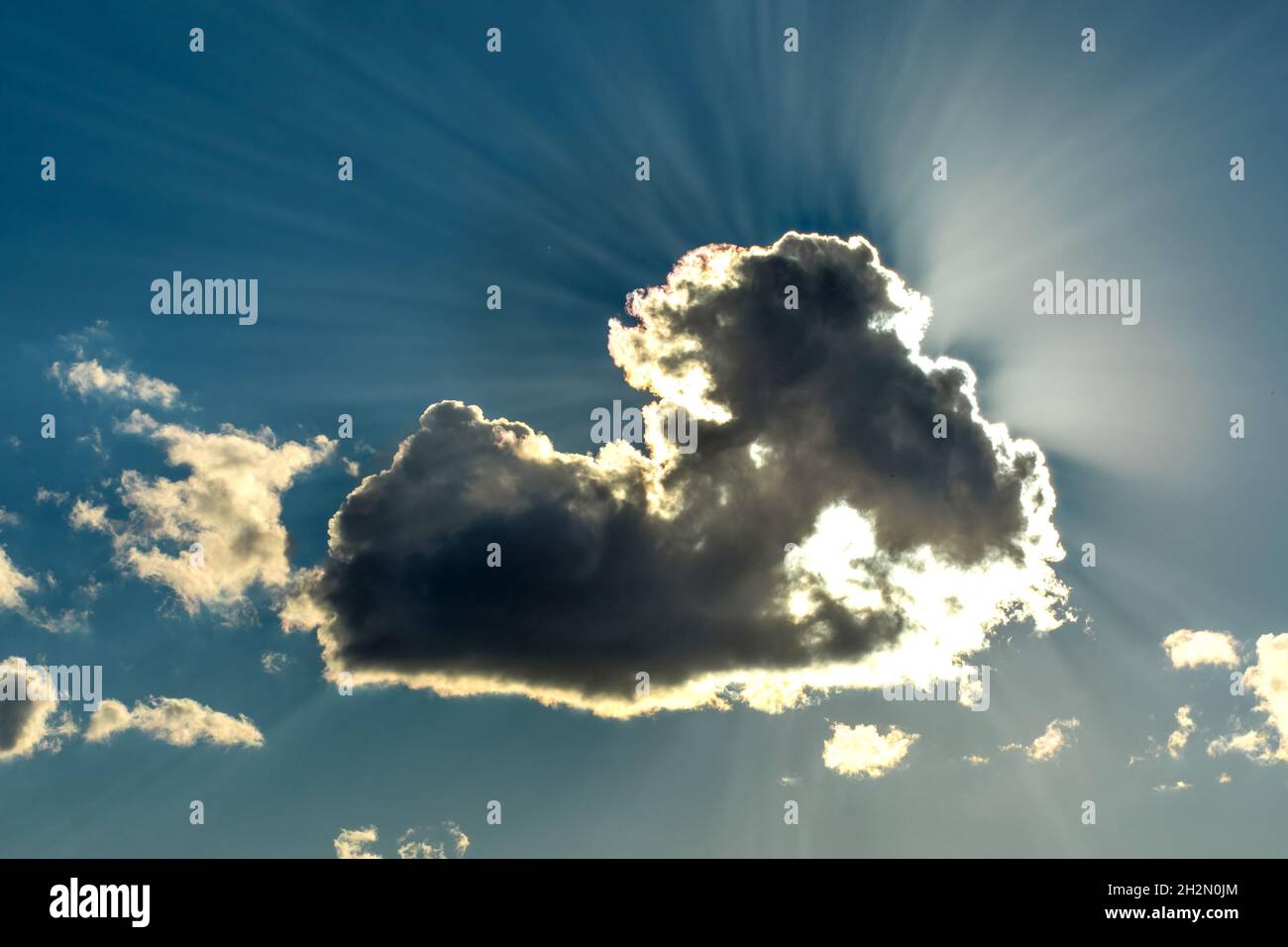 Die Sonne scheint hinter Wolken. Blauer Himmel mit Wolken und Sonnenstrahlen. Sonne versteckt hinter einer Wolke. Stockfoto